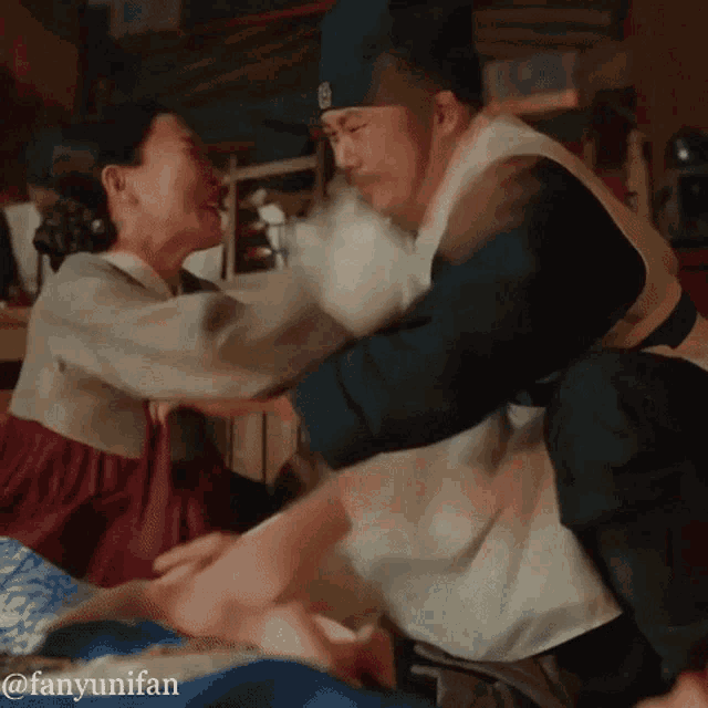 a man and a woman are having a fight and the man is wearing a hat with the letter b on it