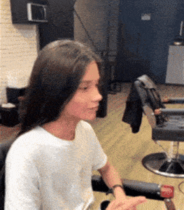 a woman is sitting in a chair in a barber shop