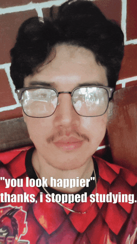 a man wearing glasses and a red shirt with the words " you look happier thanks i stopped studying "