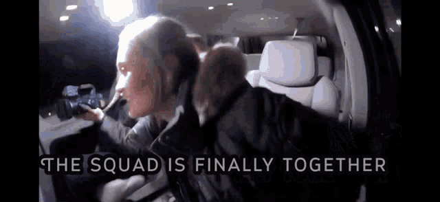 a woman is sitting in the back seat of a car with the words `` the squad is finally together '' .
