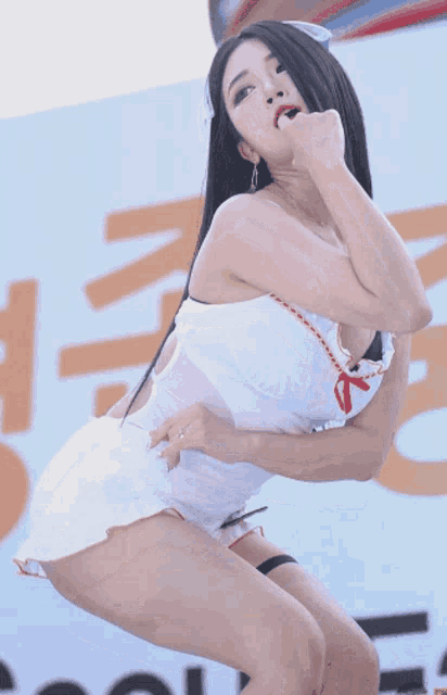 a woman in a white dress is dancing in front of a sign that says ' n ' on it
