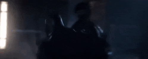 a blurry picture of a man standing in a dark room .