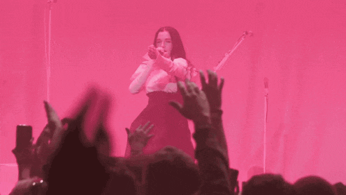 a woman is singing into a microphone in front of a crowd of people