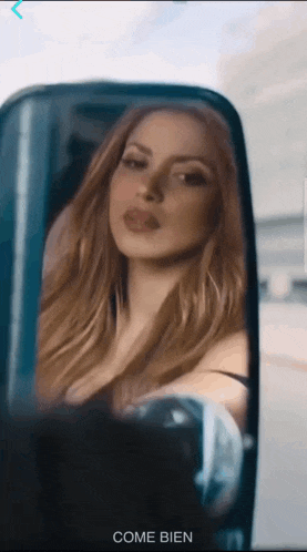 a woman in a car is reflected in the rear view mirror and the word come bien is below her