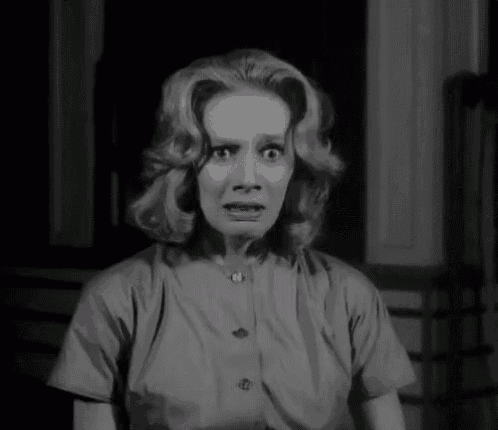 a black and white photo of a woman making a scared face .