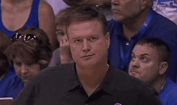 a man is sitting in a crowd of people watching a basketball game .