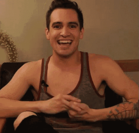a shirtless man is sitting in a chair and smiling .