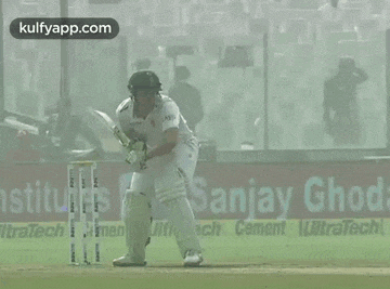 a cricket player swings a bat in front of an advertisement for sanjay ghosh cement