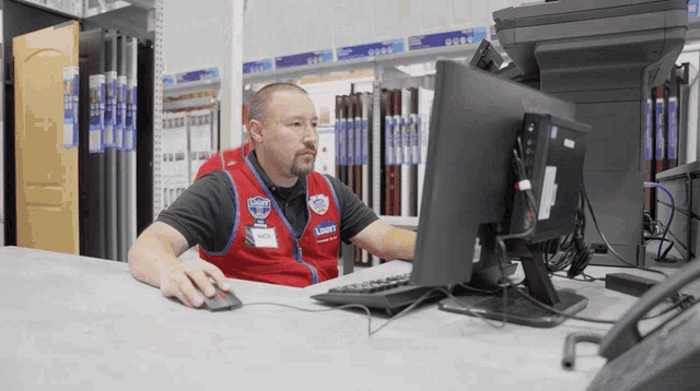 a man in a lowe 's uniform looks at a computer screen