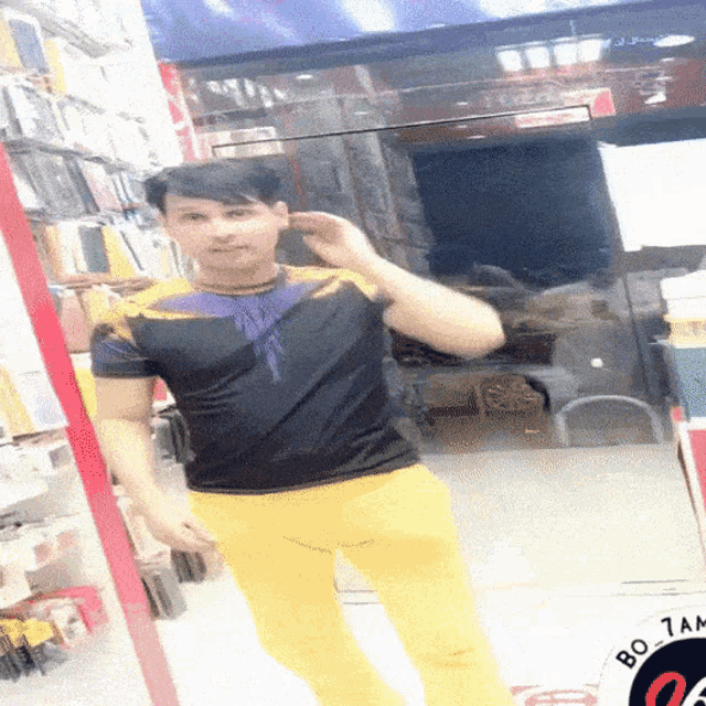 a man in a black shirt and yellow pants is standing in front of a bo tam sign