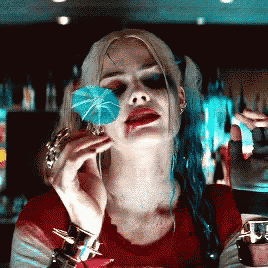 harley quinn from suicide squad is holding a blue umbrella in front of her face