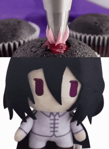 a cupcake with a flower on top of it next to a stuffed toy