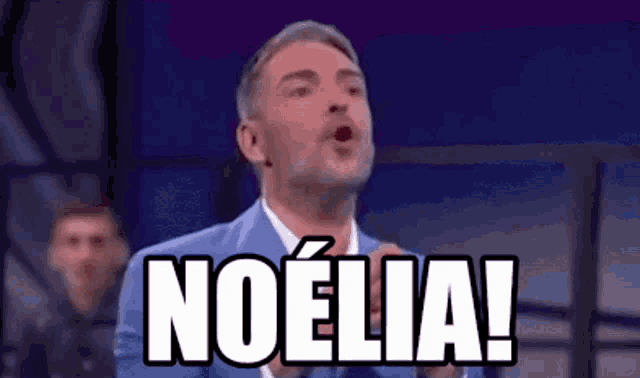 a man in a suit and tie is making a funny face and saying noelia !