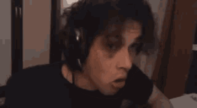 a man with curly hair is making a funny face while looking at the camera .