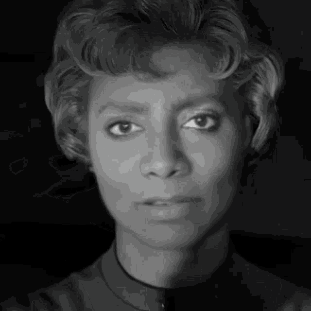 a black and white photo of a woman 's face looking at the camera