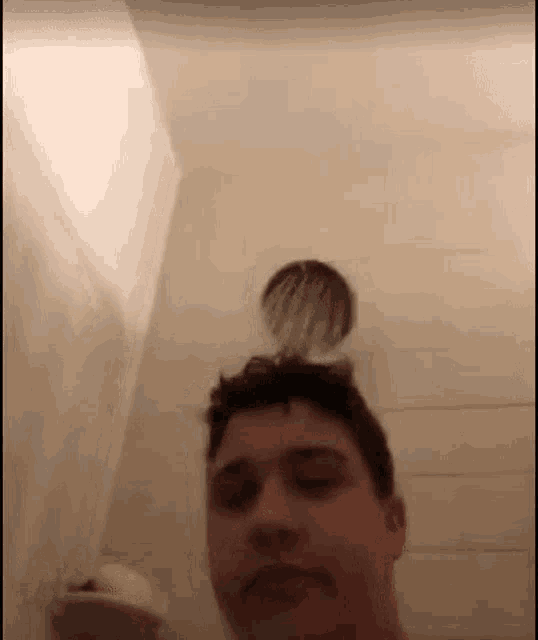 a young man is taking a selfie in a shower with a shower head on his head .