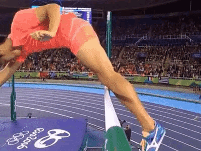 a woman is jumping over a hurdle on a track at the rio olympics .