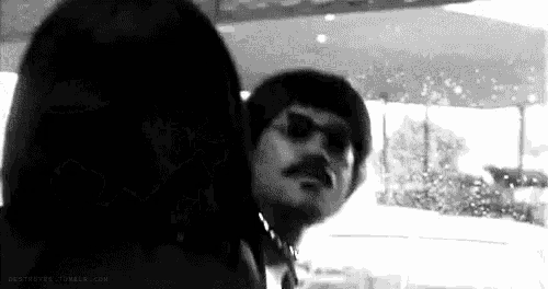 a black and white photo of a man with a mustache wearing sunglasses .