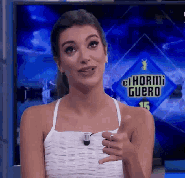 a woman is standing in front of a sign that says " el hormiguero "