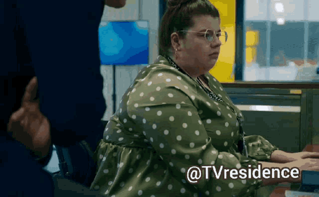a woman in a green polka dot dress is sitting at a desk with the words @tvresidence written below her