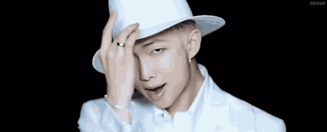 a man wearing a white hat and a white suit is smiling and looking at the camera .