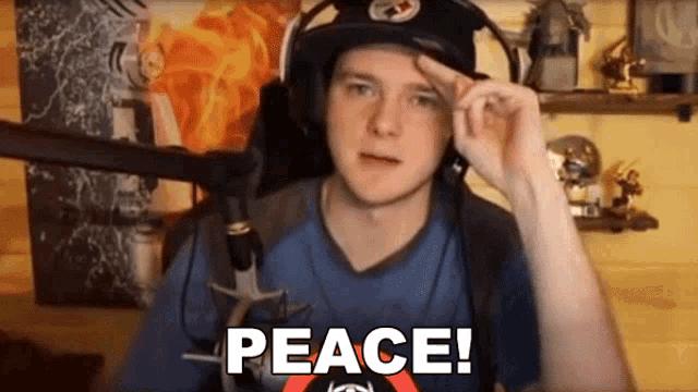 a man wearing headphones and a hat says peace in front of a microphone