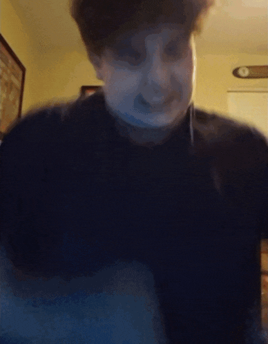 a blurry picture of a man 's face with a clock on the wall behind him