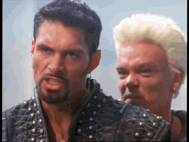 a man with a beard and a man with blonde hair are standing next to each other .