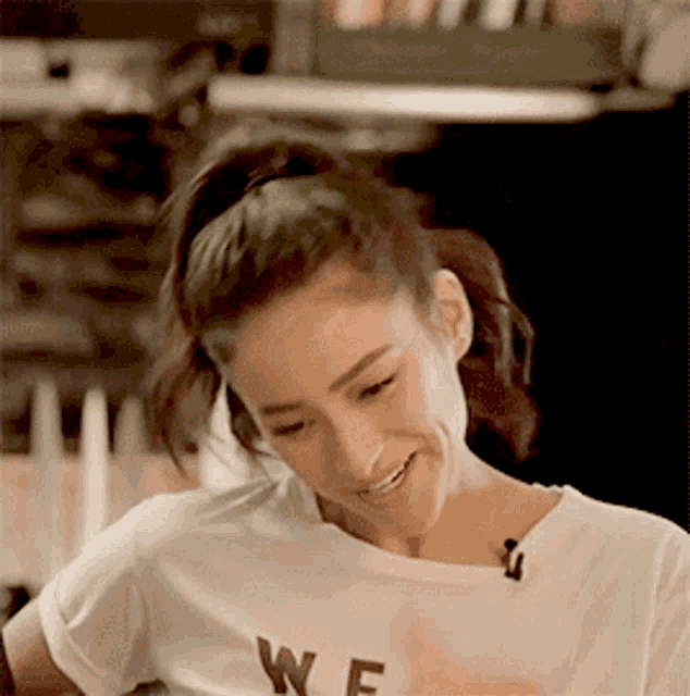 a woman wearing a white t-shirt that says we is smiling