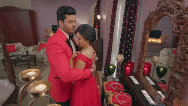 a man in a red suit is holding a woman in a red dress