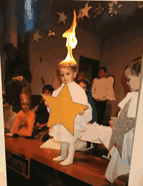 a little girl holding a yellow star with a fire on her head