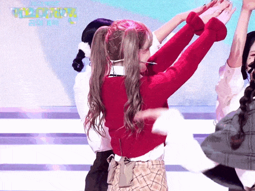 a girl in a red sweater and plaid skirt is dancing on a stage