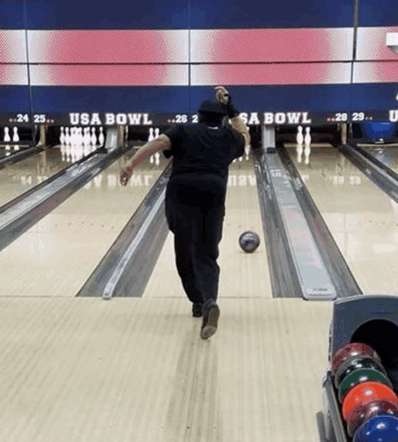 a man is bowling on a bowling alley with a bowling ball .