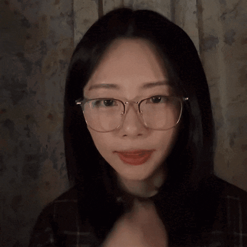 a young woman wearing glasses looks at the camera