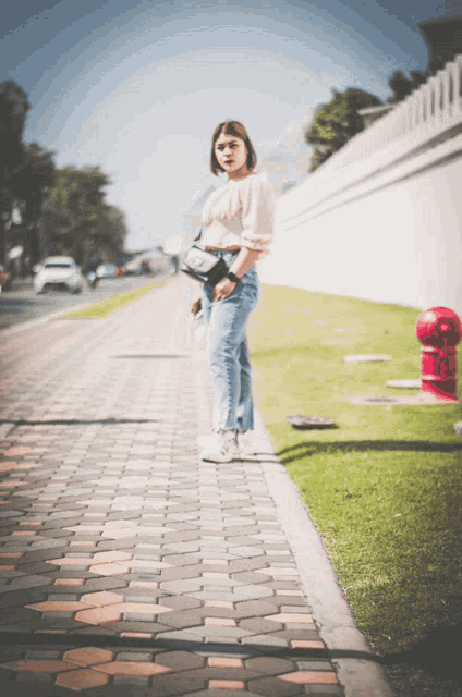a woman standing on a brick sidewalk with a red fire hydrant in the background