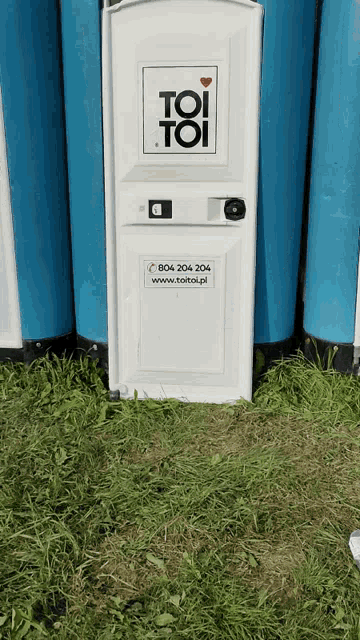 a toi toi toilet sits in the grass