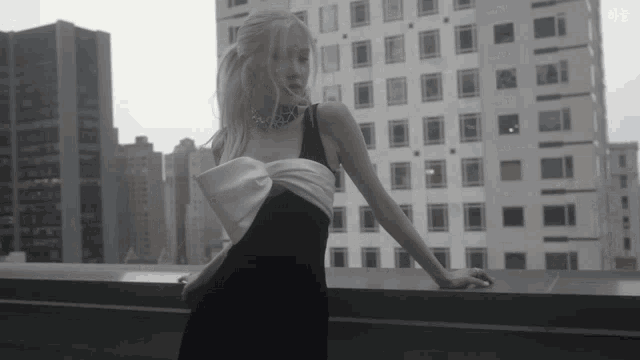 a woman in a black and white dress stands in front of a city skyline