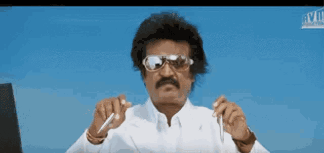 a man wearing sunglasses and a white shirt is holding a pen