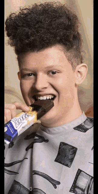 a young man with curly hair is eating a bar of libra