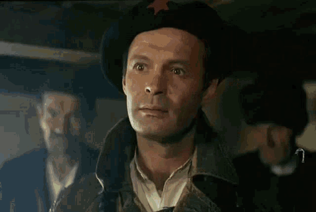 a man wearing a beret with a red star on it is standing in a dark room .
