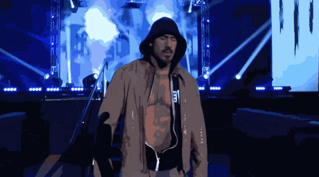 a shirtless man in a hooded jacket with the letter e on it