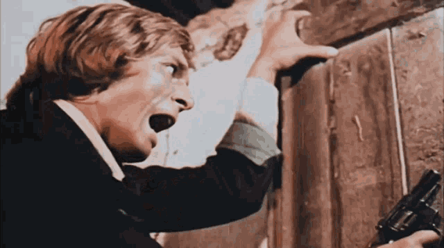 a man is holding a gun in front of a door