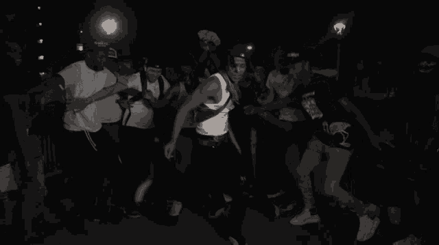 a group of people are dancing in a dark room and one of them is wearing a shirt that says skeleton on it