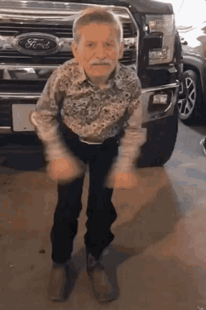 an elderly man dancing in front of a ford truck