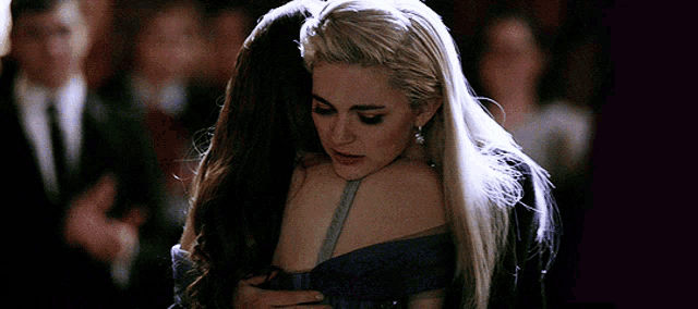 two women hugging each other with a crowd in the background