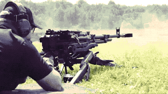 a man wearing headphones is aiming a rifle at a target