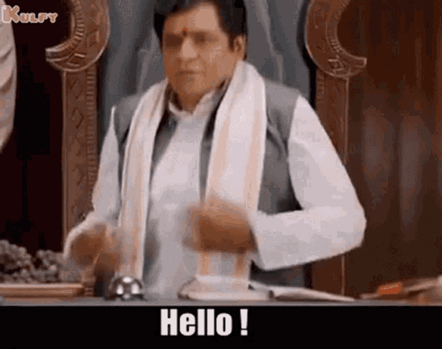 a man in a white shirt and scarf is sitting on a throne and says hello .