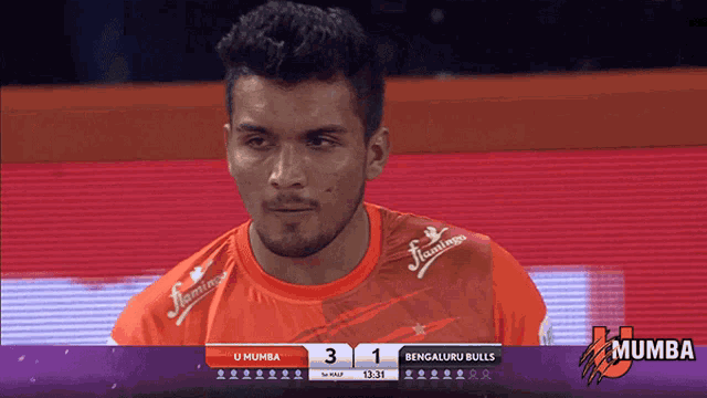 a man in an orange shirt with flamingos on the sleeves looks at the scoreboard