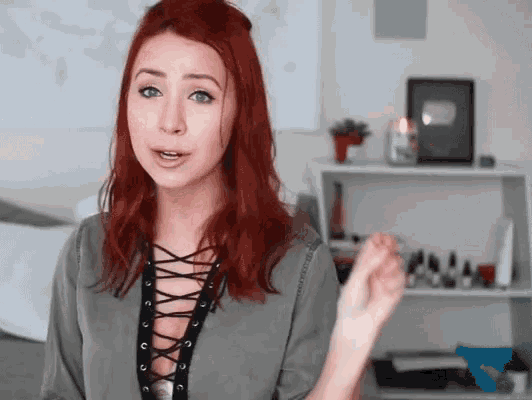 a woman with red hair and a lace up top is talking
