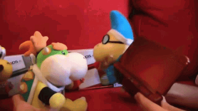 a person is holding a red nintendo ds and a stuffed animal
